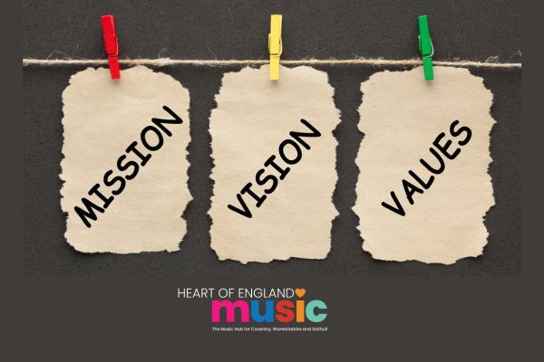 three paper tags hanging from coloured pegs with the words mission, vision and values
