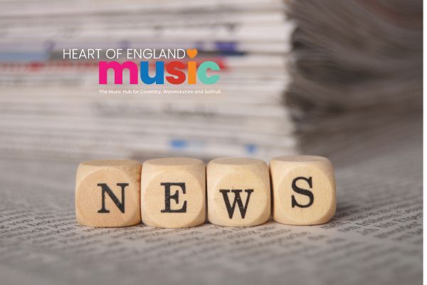 the word news spelled out with wooden letter blocks and a stack of paper in the background